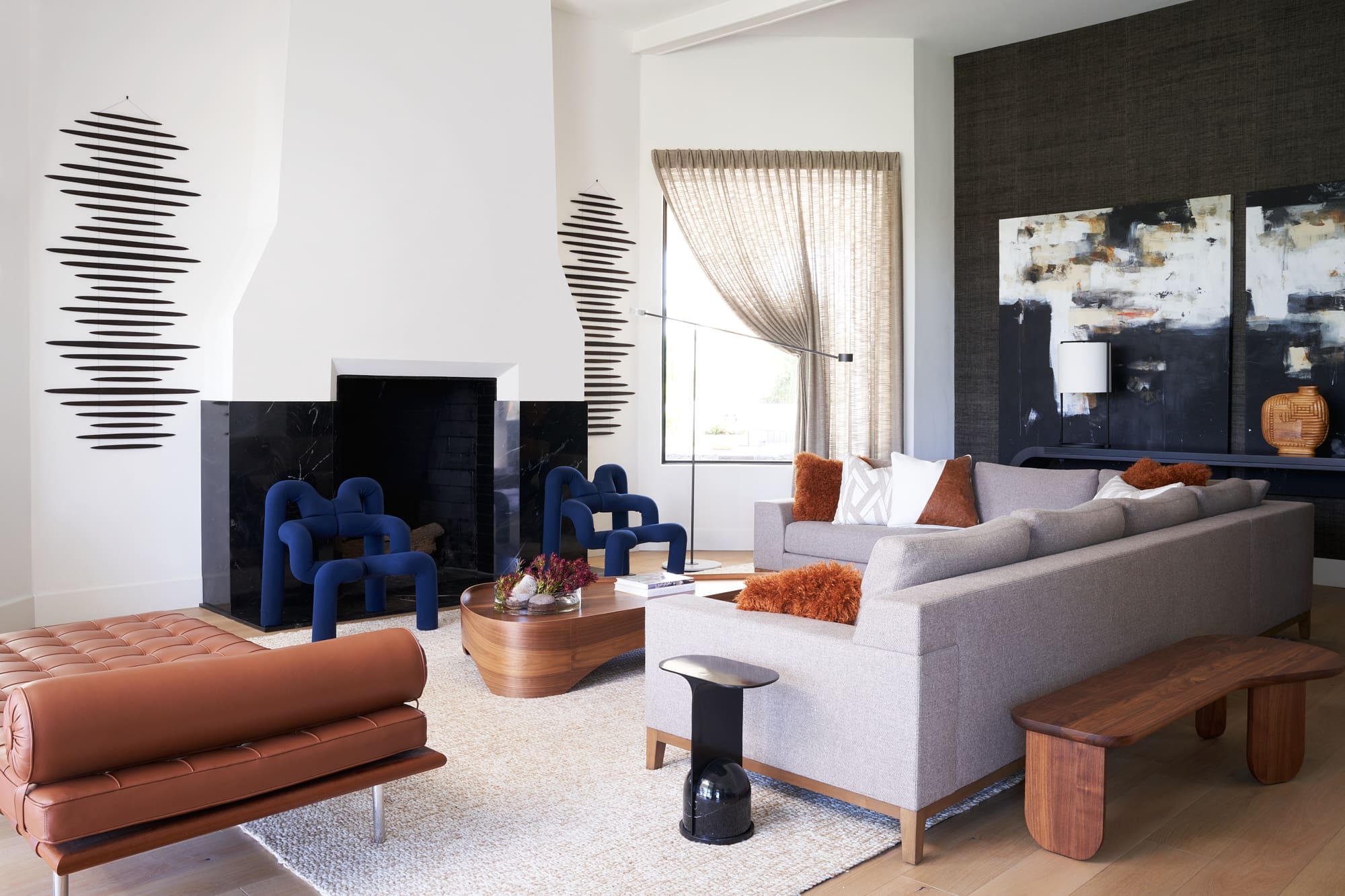 A living room with a fireplace, couches, night stand, decorative wall elements, and painting.